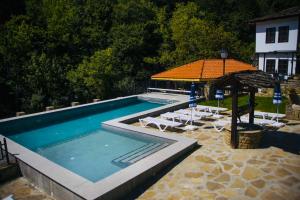 a swimming pool with chairs and an umbrella at Бекяровата къща in Spasovtsi