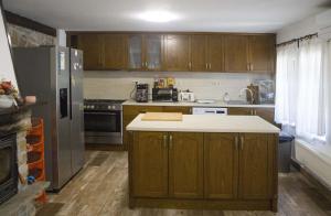a kitchen with wooden cabinets and a stainless steel refrigerator at Бекяровата къща in Spasovtsi