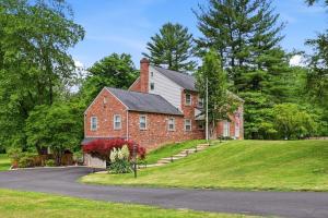 a red brick house on a hill with a driveway at 4 BR Suburban Escape - Pool, Tennis, Trails, Gym in Newtown Square