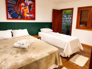 two beds in a room with a painting on the wall at Casa Garten by Concavus in Campos do Jordão