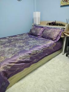 a bed with a purple comforter in a bedroom at Aura Home Kalasin in Kalasin