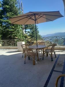 a table and chairs with an umbrella on a patio at Woodford Ayubia in Ayubia