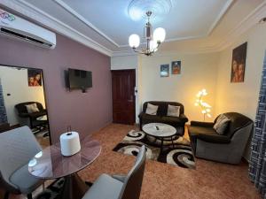 a living room with chairs and a table and a tv at Regal Hotel Douala in Douala