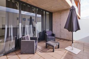 a patio with two chairs and an umbrella on a building at Aeropuerto loft 8 by Azahar Stay in Manises