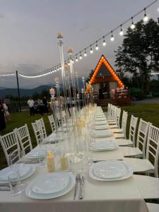 a long table with white plates and glasses and lights at Hillside Shilda in Shilda