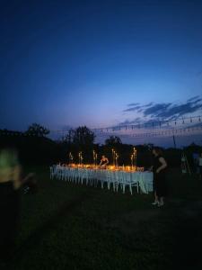 a long table with white chairs and lights at night at Hillside Shilda in Shilda +14 photos