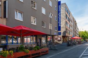 a street with tables and umbrellas in front of a building at a&o Köln Dom in Cologne