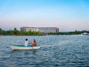 a man and woman sitting in a boat on a lake at Rixos Borovoe in Borovoye