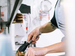 a person cutting a pizza with a pizza cutter at ibis Styles Pont du Gard Route d'Avignon in Estézargues