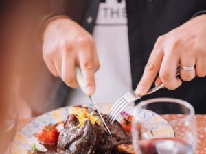 a person eating a plate of food with a fork and knife at ibis Styles Pont du Gard Route d'Avignon in Estézargues