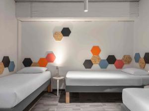 two beds in a room with colorful accents on the wall at ibis Styles Ljubljana The Fuzzy Log in Ljubljana +56 photos