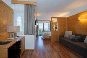a living room with a couch and a bed at Berghotel Zorzi in Alpe di Siusi