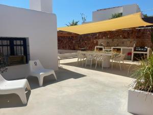 a patio with white chairs and tables and a yellow umbrella at CASA PIZZI in Agua Amarga