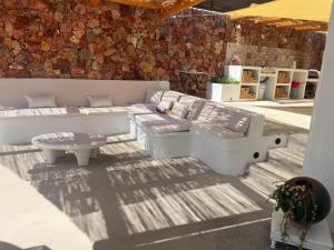a living room with white furniture and a stone wall at CASA PIZZI in Agua Amarga