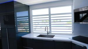 a kitchen with a sink and a window with blinds at Bright & Comfortable 2BR San Juan Getaway in San Juan +2 photos