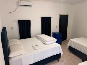 two beds in a room with black curtains at Pousada Shopping do Sono in Jaciara