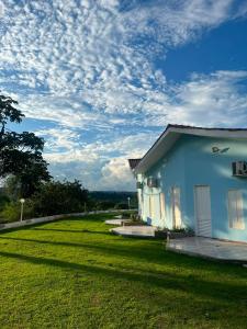 a blue house with a green lawn next to it at Pousada Shopping do Sono in Jaciara