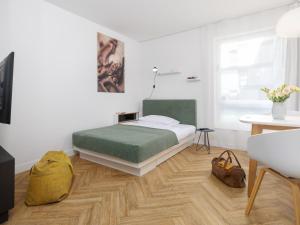 a bedroom with a bed with a green blanket and a table at smartments München Parkstadt Schwabing in Munich
