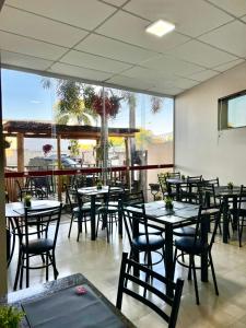 an empty restaurant with tables and chairs and a large window at Casas Novas Hotel in Penápolis