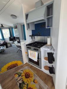 a kitchen with a stove and a living room at Izabela's Caravan - Caravan 261 in Saint Osyth