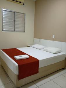 a bedroom with a bed with two towels on it at Casas Novas Hotel in Penápolis