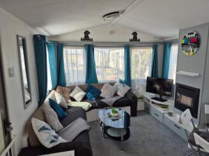 a living room with a couch and a tv at Izabela's Caravan - Caravan 261 in Saint Osyth