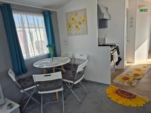 a dining room with a table and chairs and a kitchen at Izabela's Caravan - Caravan 261 in Saint Osyth +5 photos