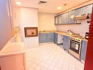 a kitchen with blue cabinets and a white tile floor at Ruru Tower Luxury Apartment in Juffair