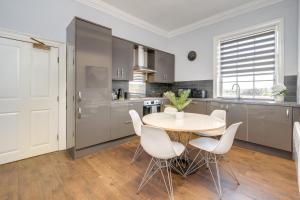 a kitchen with a round table and white chairs at Wakefield Town House Accomodation in Wakefield