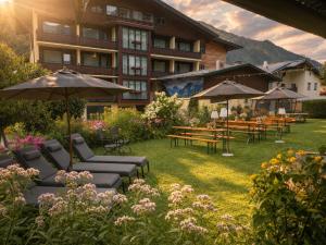a hotel yard with chairs and tables and umbrellas at Hotel Bräu in Rauris