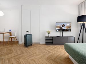 a white room with a suitcase and a tv and a table at smartments München Parkstadt Schwabing in Munich