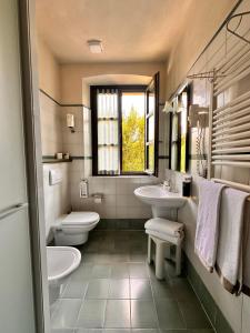 a bathroom with two sinks and a toilet and a window at Tenuta Baràc in Alba +70 photos