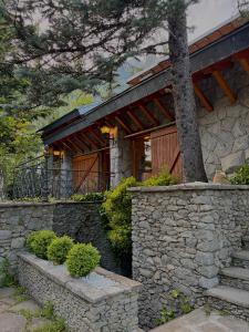 a house with a stone wall and a tree at Hotel Vallibierna in Benasque
