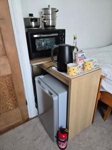 a small kitchen with a refrigerator and a microwave at BEE KIND available with shared bathroom in Glastonbury
