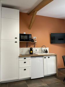 a kitchen with white cabinets and a microwave at L'Escale de Gaston in Sainte-Florence