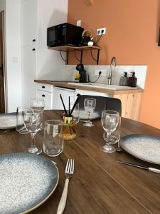 a wooden table with plates and wine glasses on it at L'Escale de Gaston in Sainte-Florence +8 photos