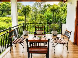 a porch with three chairs and a table on a balcony at The Oak Residence in Ragama