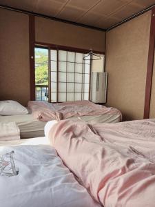 a room with three beds and a window at CocoGuesthouse in Toyama