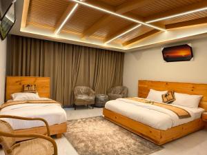 a bedroom with two beds and a tv on the wall at Pine View Hotel in Abbottabad
