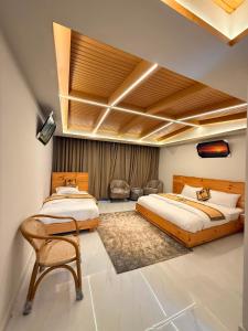 a bedroom with two beds and a chair at Pine View Hotel in Abbottabad