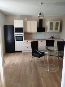 a kitchen with a glass table and black appliances at Les lilas in Moëlan-sur-Mer