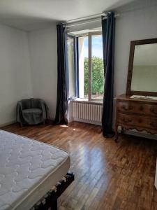a bedroom with a bed and a dresser and a mirror at Les lilas in Moëlan-sur-Mer