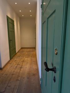 an empty hallway with a green door and a wooden floor at Gästehof Tultewitz in Naumburg