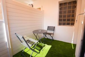 a table and chairs in a small room with green grass at Studio M Les Suites Du Roubion in Montélimar