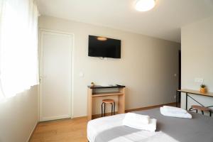 a bedroom with a bed and a desk with a tv on the wall at Studio M Les Suites Du Roubion in Montélimar