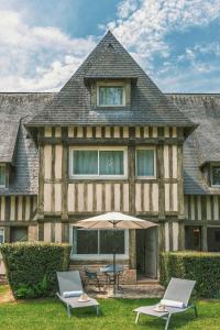 a house with two chairs and an umbrella in front of it at Les Manoirs de Tourgéville in Deauville