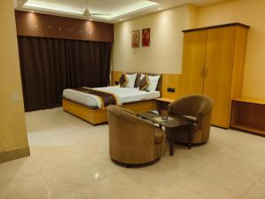 a hotel room with a bed and a table and chairs at NAKSHATRA Hotel, Restaurant & Banquet in Barddhamān +7 photos