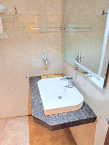 a bathroom with a white sink and a mirror at NAKSHATRA Hotel, Restaurant & Banquet in Barddhamān