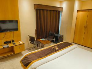a hotel room with a bed and a flat screen tv at NAKSHATRA Hotel, Restaurant & Banquet in Barddhamān