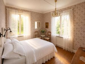 a bedroom with a white bed and two windows at Villa Fridhem, Härnösand in Härnösand